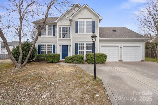 traditional-style home with roof with shingles, driveway, an attached garage, and fence