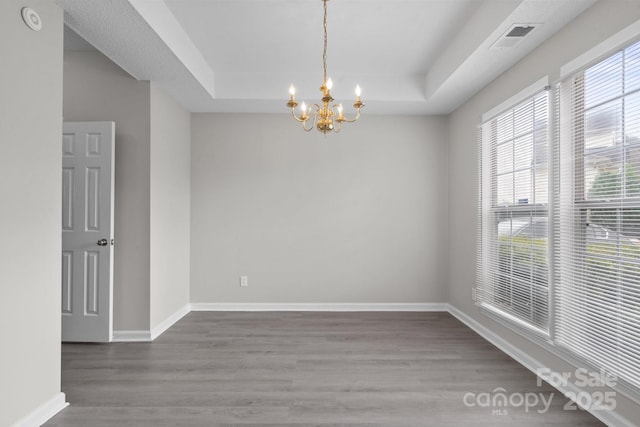 spare room featuring visible vents, a raised ceiling, and wood finished floors