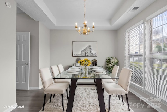 dining area with wood finished floors, a raised ceiling, visible vents, and a notable chandelier