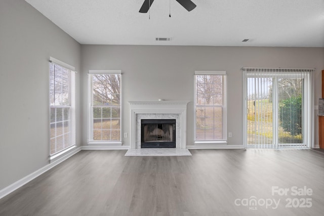 unfurnished living room with visible vents, a wealth of natural light, and wood finished floors