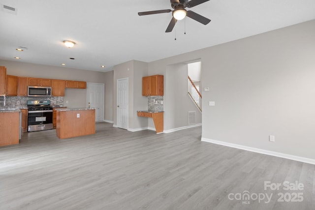 unfurnished living room with light wood-type flooring, visible vents, and baseboards