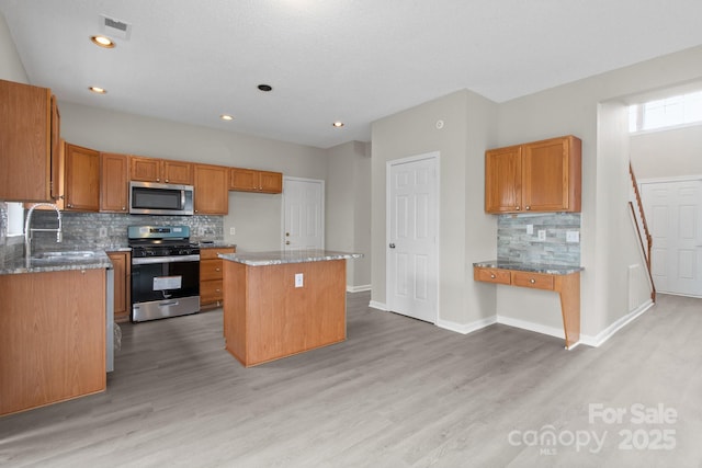 kitchen with stainless steel appliances, a kitchen island, a sink, visible vents, and light wood finished floors