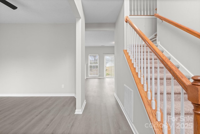 stairs with wood finished floors, visible vents, and baseboards