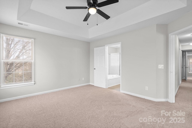 unfurnished bedroom with carpet floors, a raised ceiling, visible vents, and baseboards