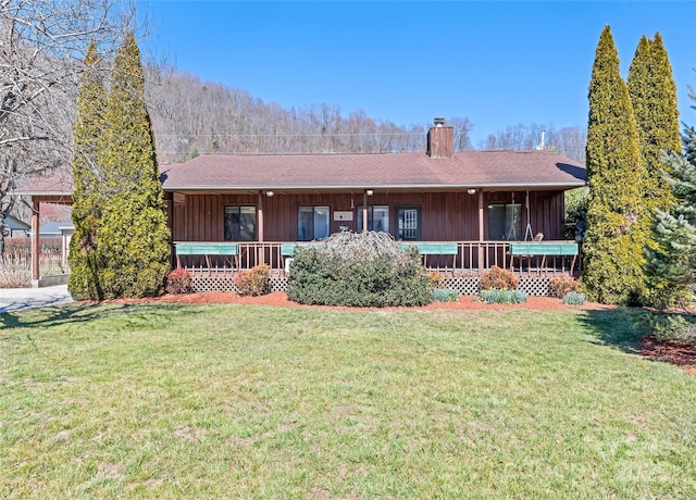 ranch-style house featuring a chimney, roof with shingles, a porch, and a front lawn