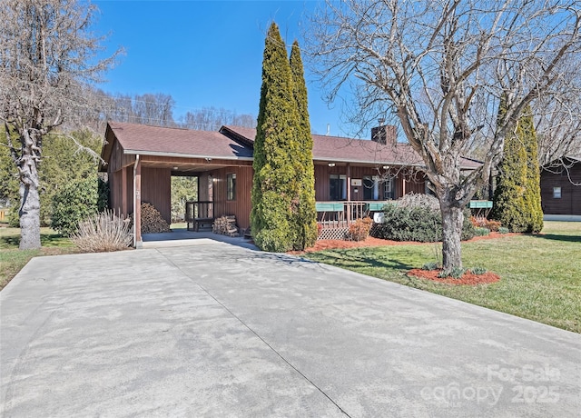 ranch-style home featuring concrete driveway, a porch, a front lawn, and a chimney