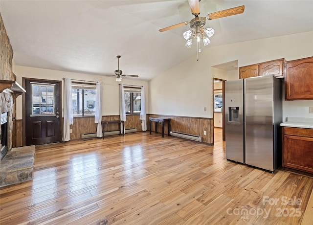 unfurnished living room featuring a baseboard heating unit, wainscoting, a fireplace, and lofted ceiling