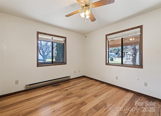 empty room featuring a baseboard heating unit, baseboards, a ceiling fan, and light wood-style floors