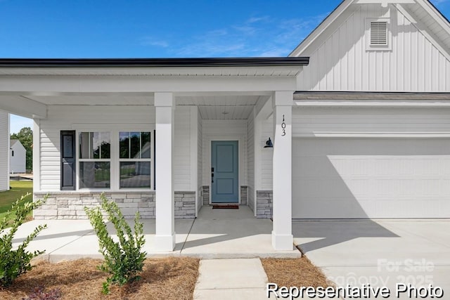 property entrance with driveway, stone siding, and board and batten siding