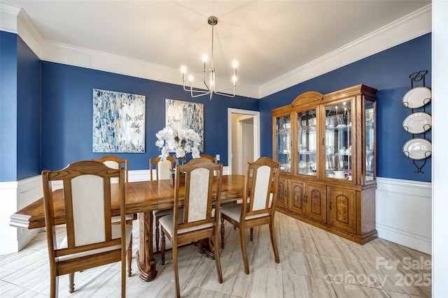 dining room featuring a chandelier, ornamental molding, and wainscoting