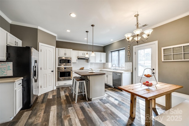 kitchen featuring appliances with stainless steel finishes, decorative backsplash, white cabinetry, and under cabinet range hood