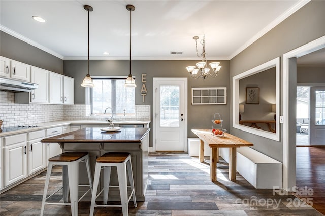 kitchen with dark wood-style floors, visible vents, under cabinet range hood, and black electric cooktop