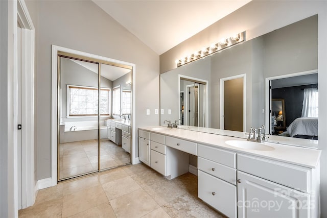 full bathroom featuring double vanity, vaulted ceiling, a sink, ensuite bath, and a bath