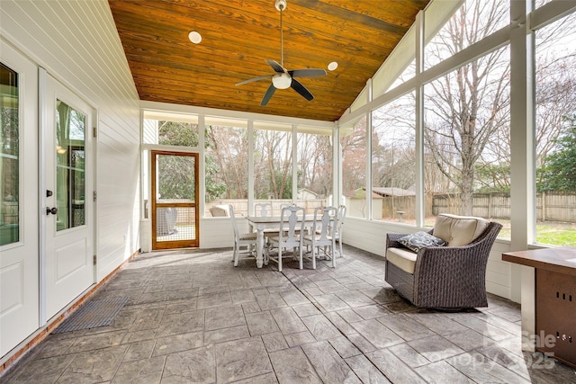 unfurnished sunroom featuring vaulted ceiling, ceiling fan, wood ceiling, and a healthy amount of sunlight