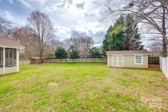 view of yard featuring a sunroom, a fenced backyard, a storage unit, and an outdoor structure