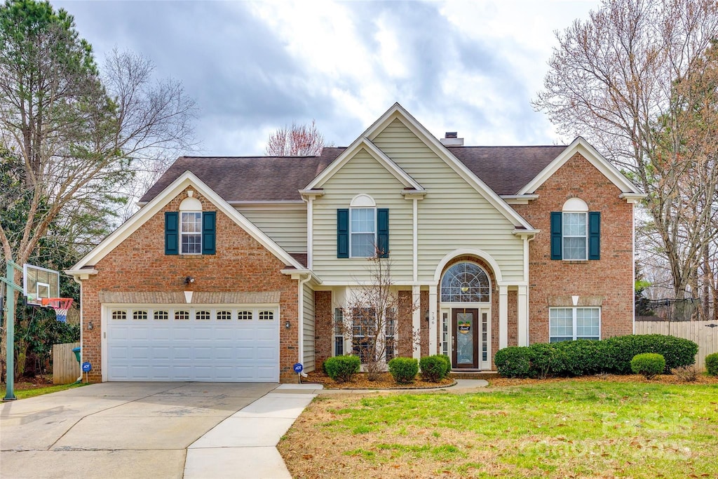 traditional-style home with a chimney, brick siding, fence, and driveway