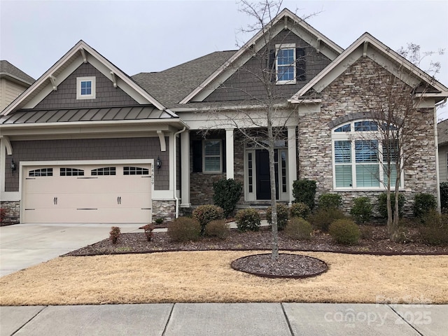 craftsman-style house featuring stone siding, metal roof, concrete driveway, and a standing seam roof