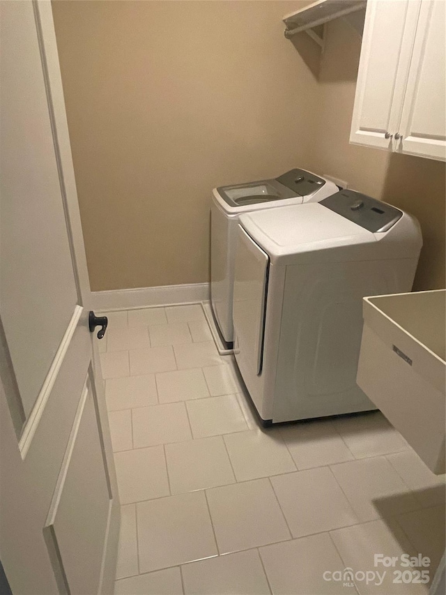 laundry area featuring washer and clothes dryer, a sink, cabinet space, and baseboards