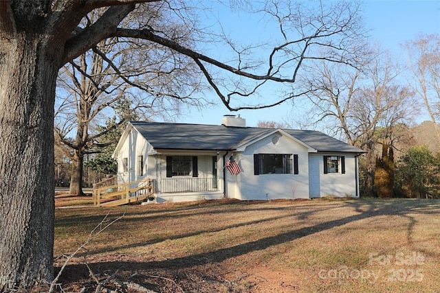 view of front facade with a porch, a chimney, and a front yard