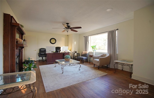 living room featuring ceiling fan, dark wood-style flooring, a fireplace, and baseboards