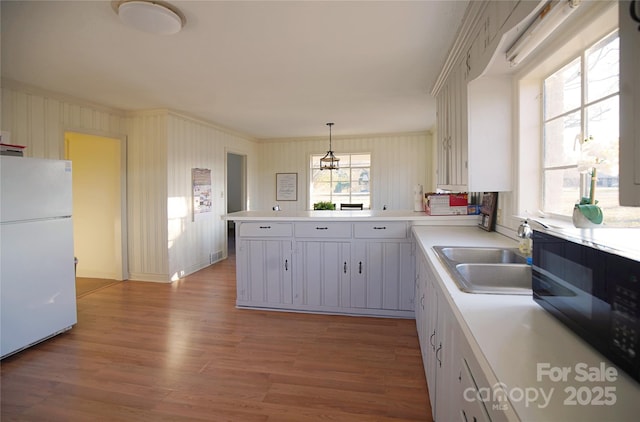 kitchen featuring a sink, hanging light fixtures, light countertops, and freestanding refrigerator