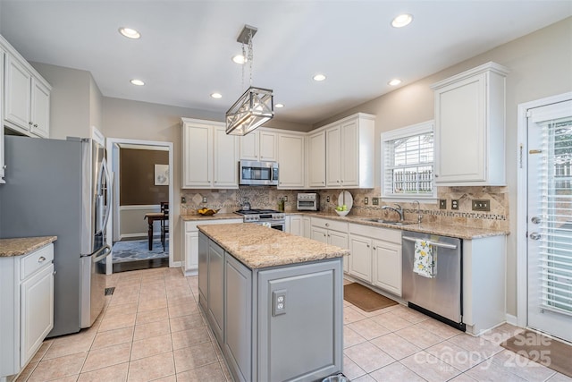 kitchen with stainless steel appliances, a center island, white cabinets, and light tile patterned floors