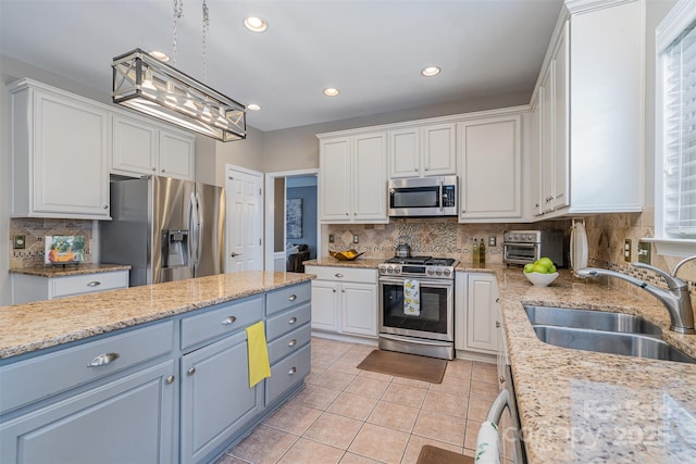 kitchen with light tile patterned floors, stainless steel appliances, a sink, white cabinetry, and tasteful backsplash