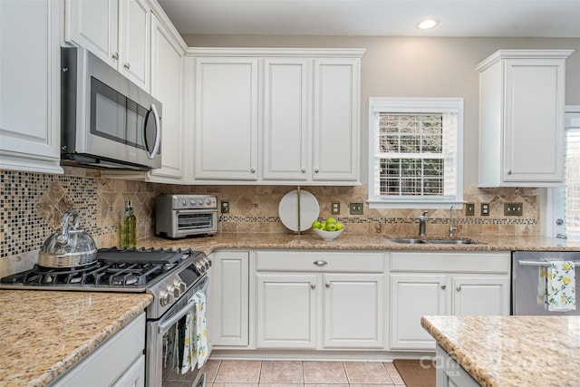 kitchen featuring white cabinets, stainless steel appliances, a sink, and light tile patterned flooring