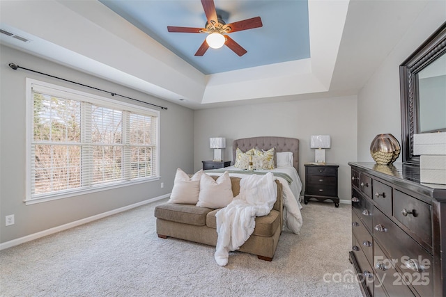 bedroom featuring light carpet, baseboards, visible vents, and a raised ceiling