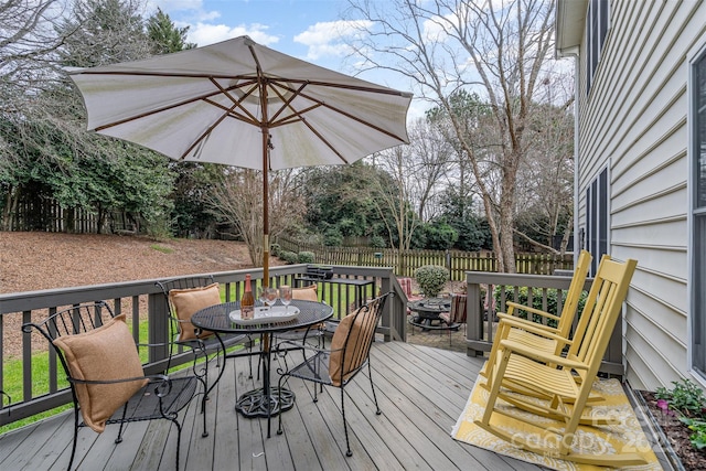 wooden deck with outdoor dining area and a fenced backyard