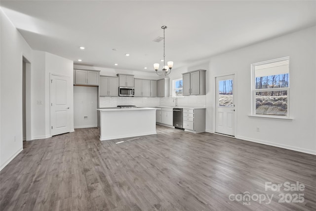 kitchen featuring a kitchen island, gray cabinets, stainless steel appliances, light countertops, and pendant lighting