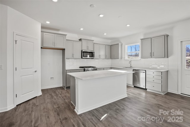 kitchen with light countertops, appliances with stainless steel finishes, a sink, and a center island