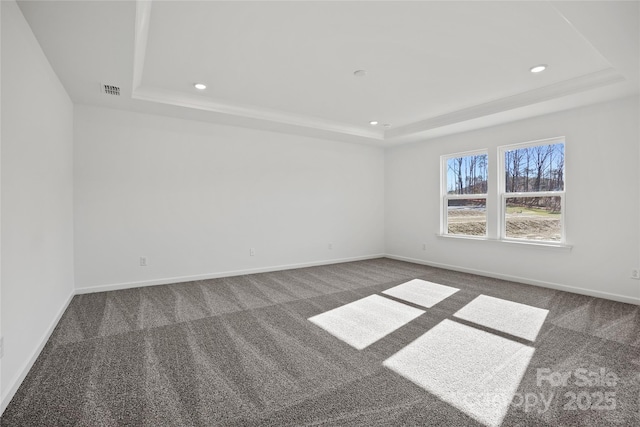 unfurnished room with baseboards, a tray ceiling, and dark colored carpet