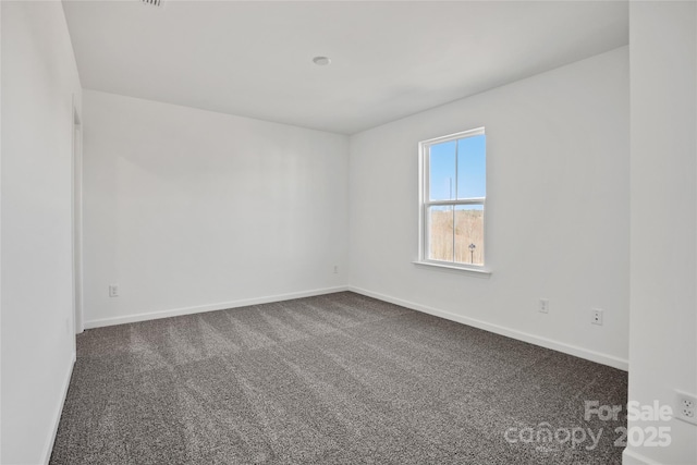 unfurnished room with dark colored carpet and baseboards