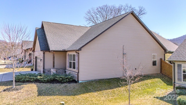 view of side of home with stone siding, roof with shingles, and a lawn