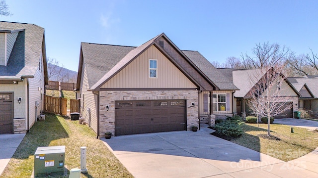 view of front of property featuring a garage, concrete driveway, roof with shingles, fence, and a front yard