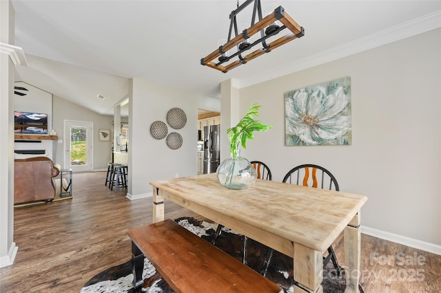 dining space featuring lofted ceiling, crown molding, baseboards, and wood finished floors