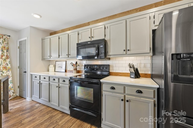 kitchen featuring recessed lighting, light countertops, decorative backsplash, wood finished floors, and black appliances