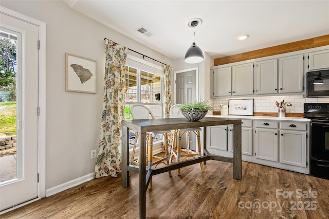 kitchen featuring baseboards, visible vents, decorative backsplash, dark wood-style flooring, and black appliances