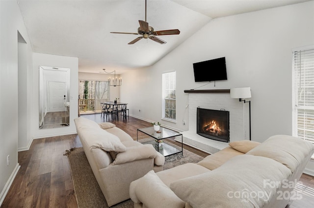 living room with baseboards, lofted ceiling, dark wood-style floors, ceiling fan, and a brick fireplace