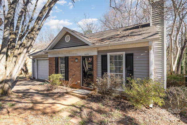 view of front facade featuring a garage, driveway, a chimney, and brick siding