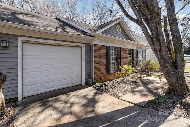 view of front of home with driveway, roof with shingles, a garage, and brick siding