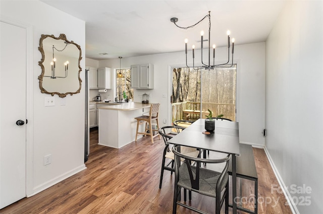 dining room featuring a notable chandelier, baseboards, and wood finished floors