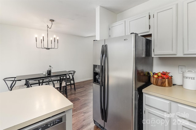 kitchen with wood finished floors, an inviting chandelier, stainless steel appliances, light countertops, and white cabinetry