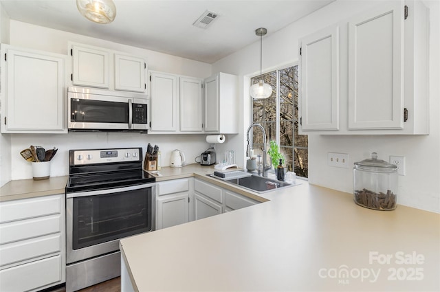 kitchen featuring visible vents, hanging light fixtures, stainless steel appliances, light countertops, and a sink