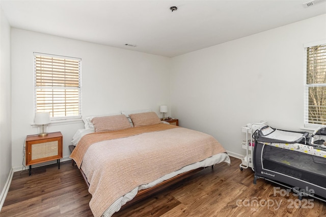 bedroom with wood finished floors, visible vents, and baseboards