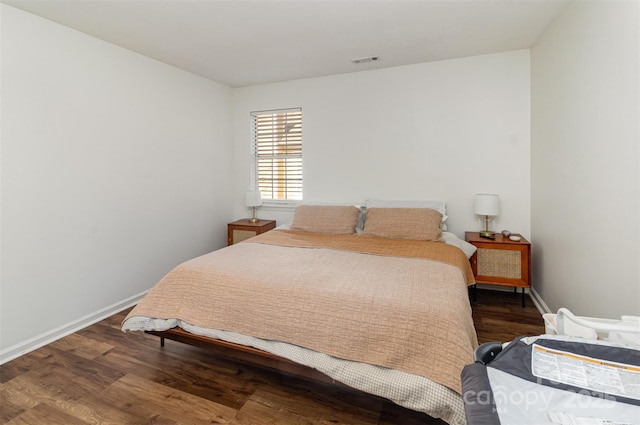 bedroom with wood finished floors, visible vents, and baseboards