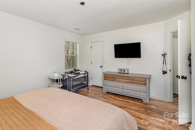 bedroom featuring light wood-style floors, visible vents, and baseboards