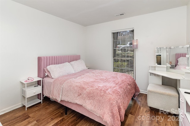 bedroom with visible vents, baseboards, and wood finished floors