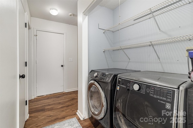 laundry area featuring laundry area, washing machine and dryer, baseboards, and wood finished floors